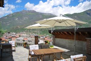 a patio with a table and chairs and an umbrella at B&B Casa Val in Quincinetto