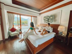 a man and woman sitting on a bed in a hotel room at Pai Cherkaew Boutique House in Pai