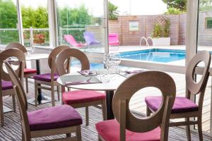 un patio con mesa, sillas y piscina en Best Western Hotel Le Bordeaux Sud, en Gradignan