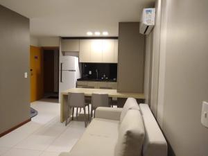 a living room with a couch and a kitchen at Apartamento quarto e sala - Iloa Residence II in Barra de São Miguel