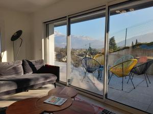 a living room with a couch and a large glass window at Appartement Thiou in Sévrier