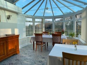 a conservatory with a table and chairs and a glass ceiling at Graceland Farm B&B in Brockenhurst