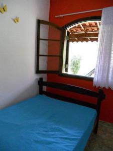 a bedroom with a blue bed and a window at Chale Colonial in Ubatuba