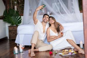 a man and woman sitting on a bed drinking wine at Duck House Sasaima in Sasaima