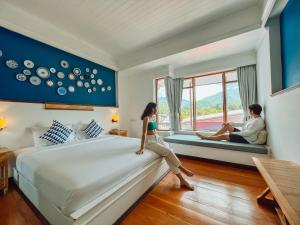 a woman sitting on a bed in a hotel room at Pai Cherkaew Boutique House in Pai