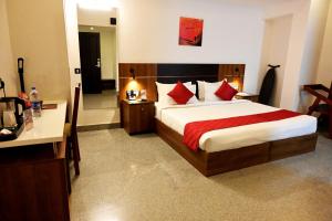 a bedroom with a large bed with red pillows at Hotel Thamburu International in Trivandrum