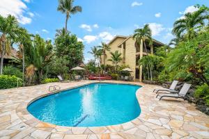 a swimming pool with chairs and a house at Kalani Kai#104 in Kailua-Kona