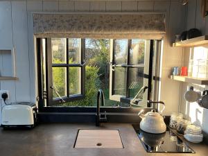 a kitchen counter with a sink and a window at Cocklebury Farm in Pewsey