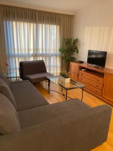 Apartment Madrid Barajas في مدريد: غرفة معيشة بها أريكة وتلفزيون