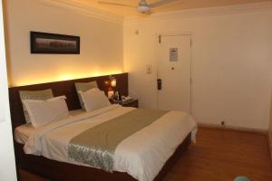 a bedroom with a large bed with white sheets at Chacha Inn The Garden Retreat in Mount Ābu