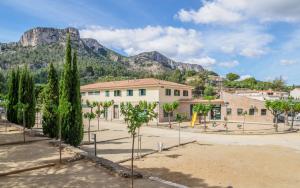 a building with trees and mountains in the background at Camping Alberg Municipal Tivissa in Tivissa