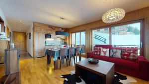 a living room with a red couch and a table at Hauts de Veysonnaz SAUNA & VIEW apartments in Veysonnaz