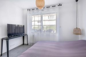 um quarto com uma cama e uma televisão de ecrã plano em Belle maison a proximite de la plage de la Baule em La Baule