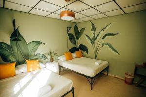 a room with a bed and a couch with plants on the wall at Hostel Travelers Santiago in Santiago