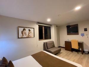 a bedroom with a bed and a chair and a desk at Hotel Patrimonio in Cuenca