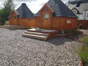 a wooden cabin with stairs in a gravel yard at Unique luxury cabin 2 in Inverness