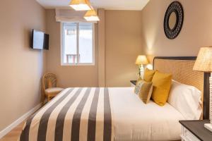 a bedroom with a bed with yellow pillows and a window at Plaza Nueva Deluxe Suite by Valcambre in Seville