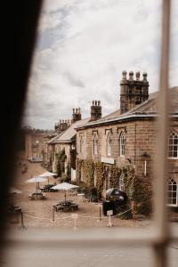an old brick building with tables and umbrellas in front of it at The Boar's Head in Harrogate