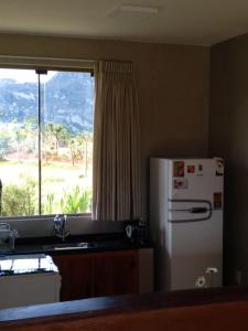 Una cocina con un refrigerador blanco y una ventana. en Chalé Paz Central do Paraíso Lapinha da Serra, en Santana do Riacho
