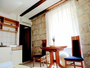 eine Küche mit einem Tisch, 2 Stühlen und einem Fenster in der Unterkunft Apartment Biline Center in Korčula