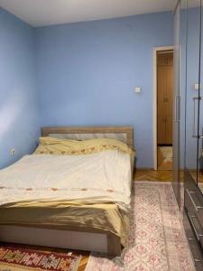 um quarto com uma cama com uma parede azul em Lovely Hotel & Apartment for rent in center of Gjilan em Gjilan