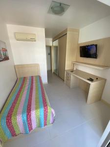 Schlafzimmer mit einem Bett, einem Schreibtisch und einem TV in der Unterkunft Costa Maggiore Residencial Resort in Cabo Frio