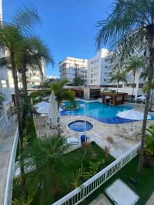 uitzicht op een zwembad met palmbomen en gebouwen bij Costa Maggiore Residencial Resort in Cabo Frio