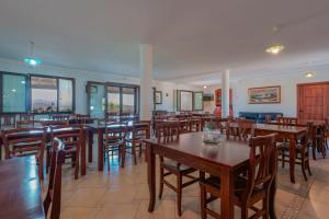 a restaurant with wooden tables and chairs and windows at L'Oasi del Cervo in Arbus