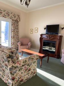 a living room with a couch and a table and a television at The Waring House in Picton