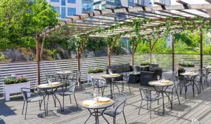 un patio con mesas y sillas bajo una pérgola en Brommavik Hotel, en Estocolmo