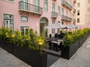 an outdoor patio with tables and plants in front of a pink building at Portugal Boutique Hotel in Lisbon