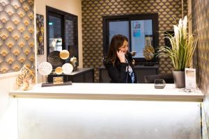 a woman talking on a cell phone behind a counter at Hotel de la Terrasse in Berck-sur-Mer