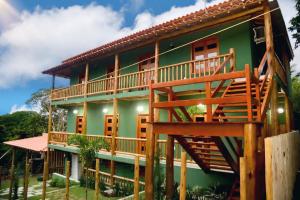 a green house with a deck on the side of it at Pousada encanto do mar, Nova caraiva-Ba in Porto Seguro
