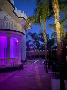 ein Resort mit violetten Lichtern an einem Gebäude mit Palmen in der Unterkunft Corte Vena in Bianco