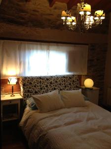 a bedroom with a bed with a window and a chandelier at Casa de piedra en Muga de Alba in Muga de Alba