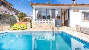 einen Pool mit zwei Stühlen und ein Haus in der Unterkunft Villa Tensi in Blanes