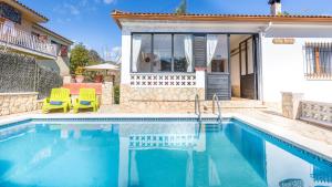 a swimming pool with two chairs and a house at Villa Tensi in Blanes