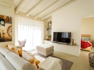 uma sala de estar com um sofá branco e uma televisão em Colosseo with wonderful lake view and swimming pool em Parzanica