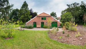 a brick house with green doors in a yard at Doppelzimmer Holthusen 25515 in Weener