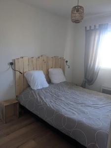 a bed with two pillows in a room with a window at Appartement 200m de l'océan avec piscine extérieure in Mimizan