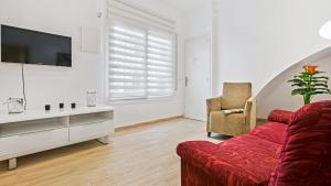 a living room with a red couch and a tv at 1 Sica - Llafranc in Llafranc