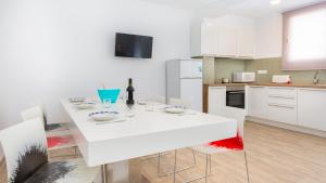 a white kitchen with a white table and chairs at 1 Sica - Llafranc in Llafranc +14 photos