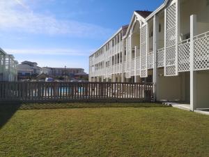 un bâtiment avec une clôture et une cour en herbe dans l'établissement Appartement 200m de l'océan avec piscine extérieure, à Mimizan