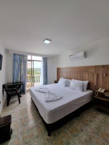 a bedroom with a large white bed and a desk at Zahira Hotel Melgar in Melgar +34 photos