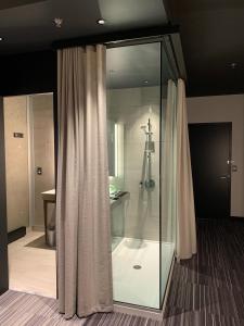 Grand Hotel TiMES Blainville-Mirabel في بلينفيل: حمام مع دش زجاجي مع ستارة دش
