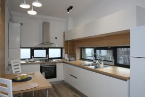 a kitchen with white cabinets and a wooden table at ResHome Apartments&Rooms in Focşani