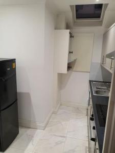 a kitchen with white walls and a black refrigerator at BEAUTIFUL ROOM In LOVELY FLAT in Woolwich