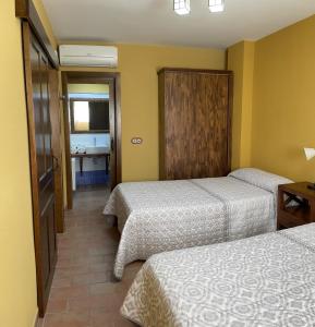 a hotel room with two beds and a bathroom at Leyendas de Monfragüe in Torrejón el Rubio