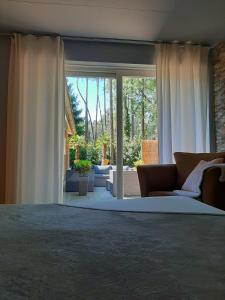 a living room with a couch and a large window at Secret Wellness Boszicht in Holten