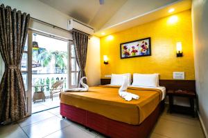 une chambre avec un lit avec un mur jaune dans l'établissement Grande Ave Maria Resort, à Candolim 84 autres photos